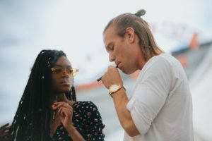 Man with bun and woman in glasses talk over vape pen from the clear cannabis.